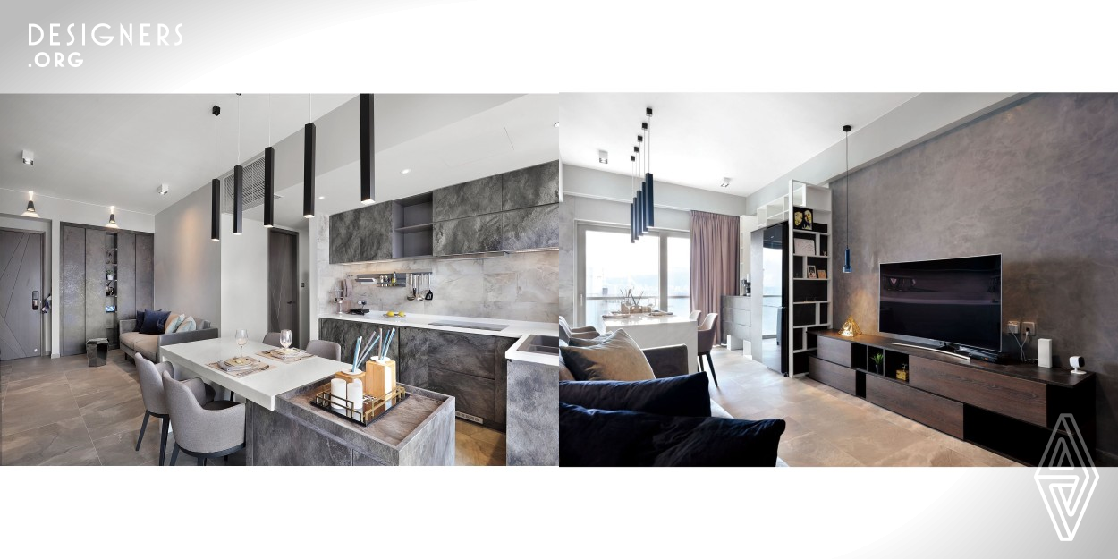 The owners also had a specific idea in mind when it came to the interior design scheme, opting for a darker color palette that Yuen adapted to prevent the property from feeling dowdy and crowded. As such, the rectangular living and dining area has been decorated largely in shades of grey and dark wood, adding a contemporary vibe. Space has been divided into two clear areas thanks to the placement of the furniture. As such, the lounge has been defined by an expansive plush grey sofa and rich wooden TV console, while the dining clearly starts an area where white floor-to-ceiling storage.