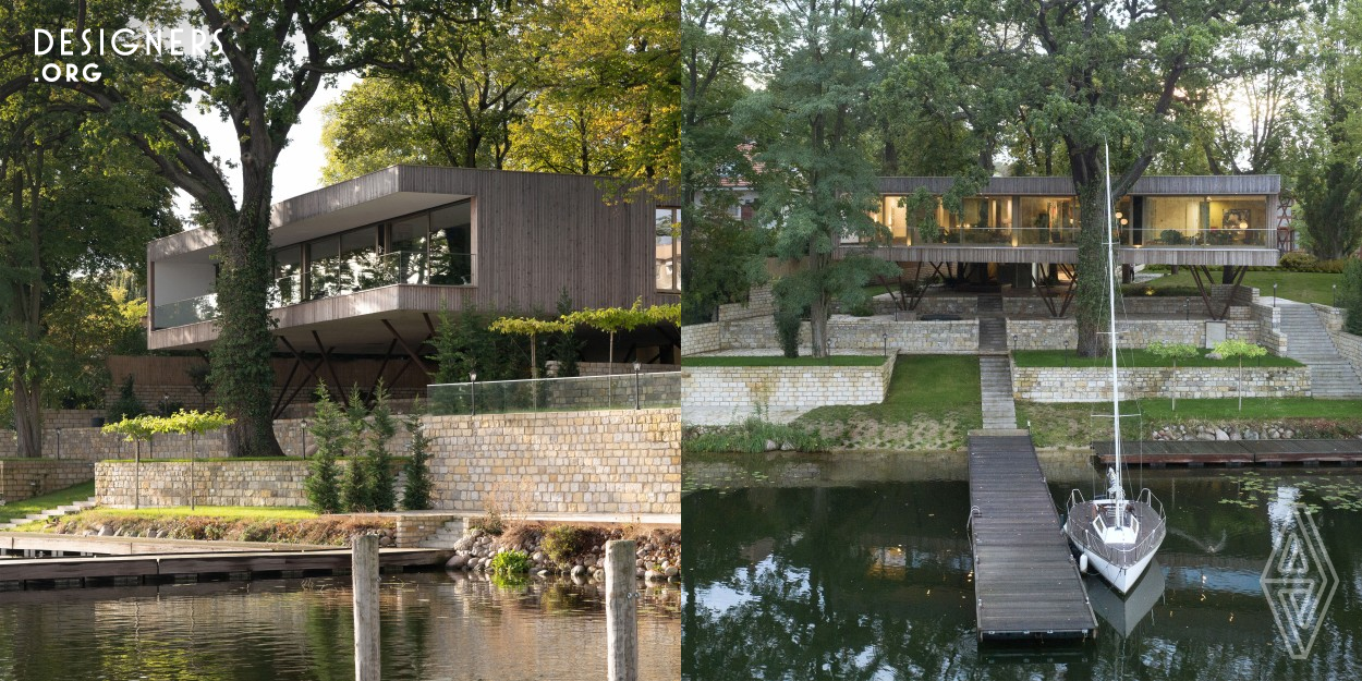 Ancient trees, the water and nature preserved terraces determined the concept of architect Carlos Zwick. Today, this passive house with its sustainable building materials integrates respectfully into its surroundings. The wooden windows connect the living spaces with the lake. The loggia seems to float above the water and a large maple tree grows through the living room. The large crowns of the ancient oaks and chestnuts take the modern tree house with its restrained wooden facade in their midst. 