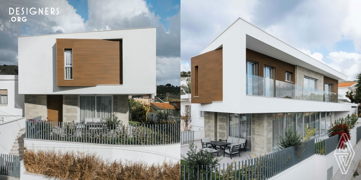 The objective of this nZeb House in Limassol was to develop a bioclimatic structure that maximizes thermal comfort by capitalizing on the local environmental conditions. The design focuses on an open orientation towards the south and scenic views, integrating the interior and exterior spaces through extensive glass surfaces. To address the need for sun protection, a distinctive white Z-shaped structure was implemented, seamlessly integrating the parking area with the main volume. Exposed concrete, large wooden surfaces, and a neutral white color palette were selected to enhance the aesthetic.