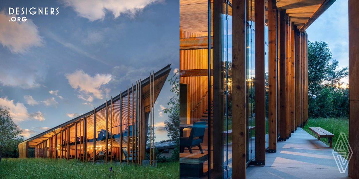 Reaching skyward toward the peaks beyond, a thin roof edge rises from an oxidized steel mass anchoring the building while outlining a curtain of glass below. Vertical timber fins based upon the Fibonacci sequence echo the slender blades of surrounding native grasses, grounding the translucent façade into the terrain. Defying the urban context of nearby monolithic structures, the graceful, slender building is nestled within a sliver of flora having taken its cue from the natural setting by reframing a connection to the landscape.