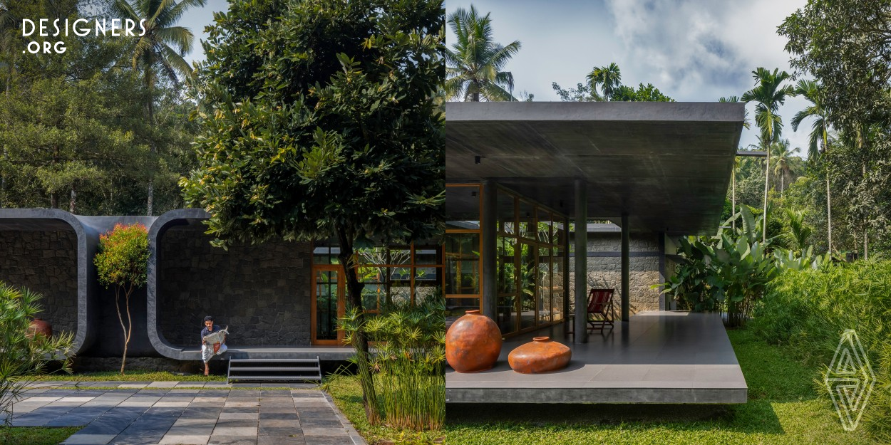 A serene retreat nestled in nature's embrace, this single story four bed house in northern Kerala, near Wayanad, is a harmonious blend of simplicity and uniqueness. Designed to respect its surroundings, the dark textured building features asymmetric c shapes mirroring a central tree. An open courtyard and wide sit out seamlessly integrate indoors with outdoors, while a minimalist interior showcases thoughtful furniture design. Rubble masonry and glass windows with wooden frames create a rustic yet modern aesthetic, echoing the tranquility of its natural setting.