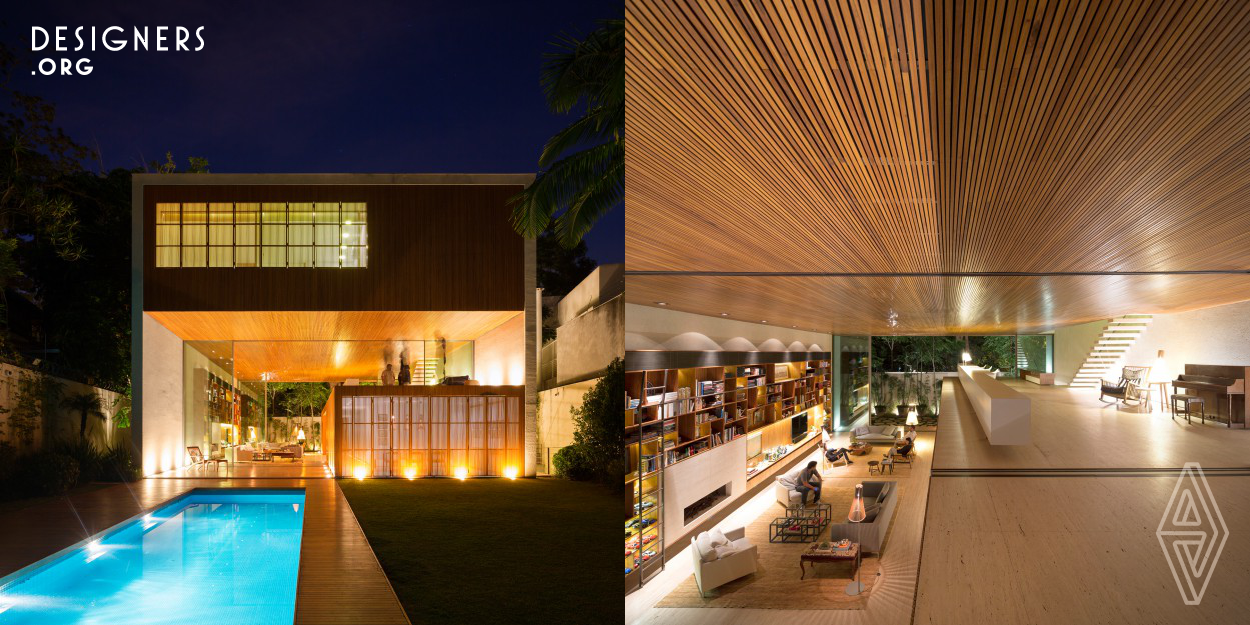 A wooden volume in line with the eastern façade – with a little more 2.85m high and19m long – rests within a ceiling height of 5.15m and 11.75 in the front.  Configuring a permeable space between the entrance and the back of the lot, the living room is the emptiness that results from this organization of the plan on this lot. The space is delimited – together with the eastern façade – by a wooden shelf that contains the library and a fireplace. This is the architectural design of Tetris House, located in Sao Paulo.  
