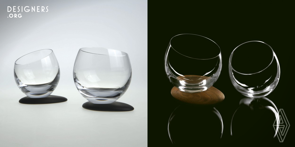 Egg-shaped crystal glasses with a sloped cut. A simple drop of vitreous liquid, a natural lens, captured in vivacious crystal glasses that joyfully rock on their roundness, while maintaining their stability through thoughtful arrangement of materials. Their rocking creates a relaxed and fun atmosphere. Glasses fit discretely to the palm when held. In symbiosis with softly designed, handmade coasters from walnut or xylite - ancient lumber. Complemented by ellipse-shaped walnut trays for three or ten glasses and a finger-food tray. The trays are rotatable due to their smooth elliptic shape.