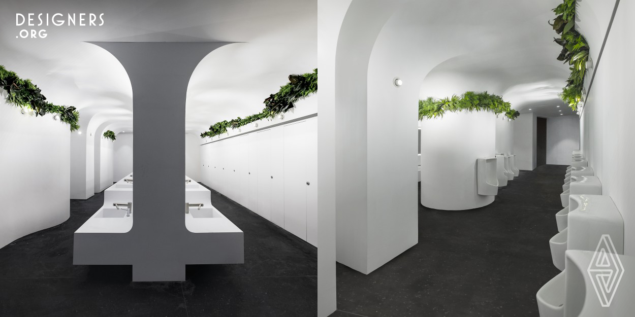 A bright grotto–a contemporary abstraction of nature–is the design concept for this underground washroom. Sustainability, spatial sculpting, human comfort drive the design. The grotto retains the original layout, uncovers two round, tilted square columns to form a unique white mass; seamless curve surfaces diffuse light and omit dirty edges. Plants, irrigated by filtered greywater, purify the air, add life and colors. The original sandstones are crushed as gold aggregates of the new terrazzo floor. Integrated tap-hand dryer, waterless urinal and toilet largely reduce water-use and waste.