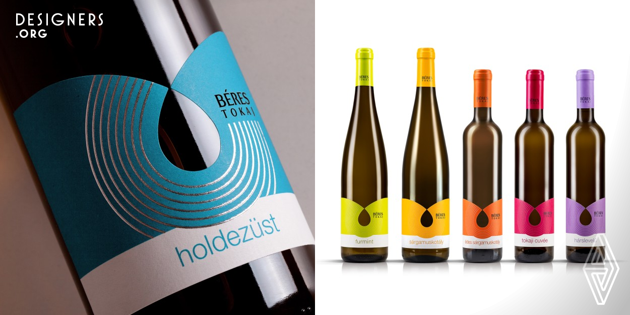 The wine label design was inspired by the drop shaped logo of the winery's parent company. The company is a pharmaceutical company whose first product was the Beres Drops. The central element of the design is cut drop, which occurs as a continuation of two arcs. The arches symbolize the fertile hills of the area from which the wine was born, which appears as a drop. The line pattern represents the vine stocks. The base wines are colorful, youthful, the premium wines are more severe, distinguished by more subdued colors and metallic stamp foils from each other.