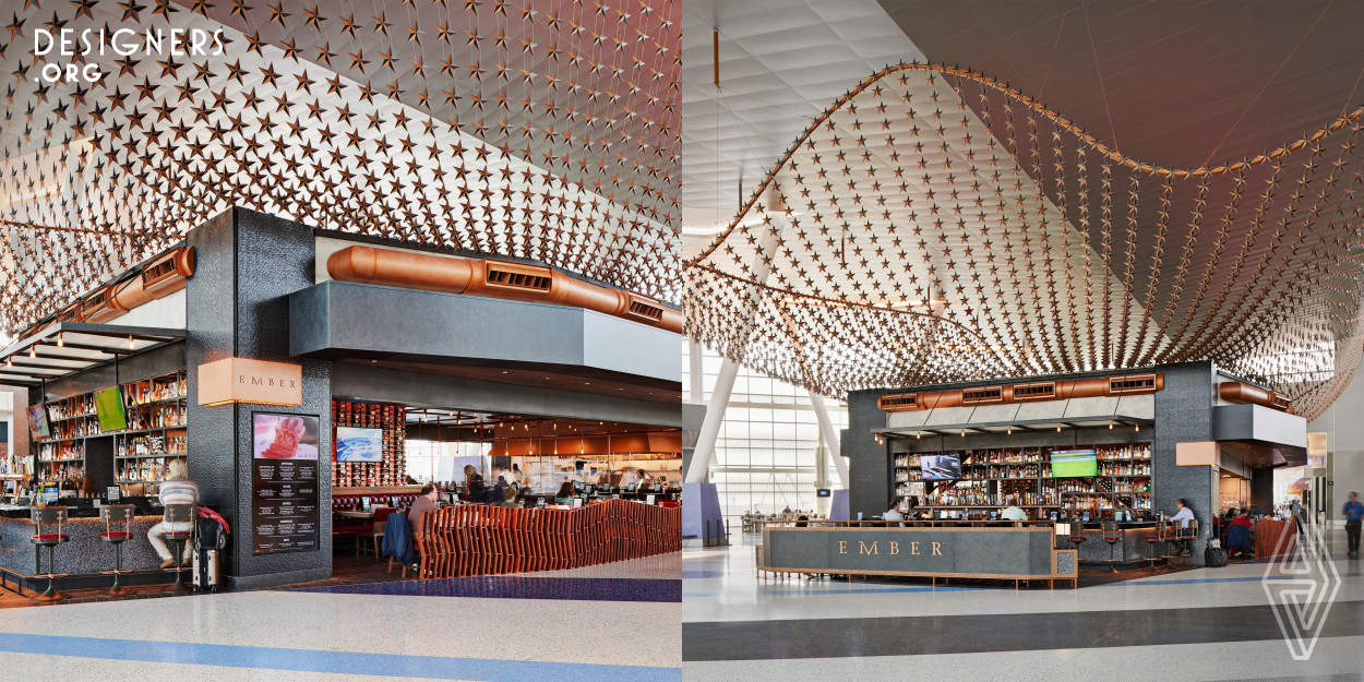 At Ember, classic materials such as black and white tiles, copper, blackened metal, and wood bring the elegance of traditional urban steakhouses to the center of Houston's George Bush Intercontinental Airport. Ember has a 360-degree exposure to the terminal and features a canopy of 6,225 copper Texas stars floating above. Diners sit under a wood plank ceiling filled with copper pipe chandeliers and exposed Edison bulbs. The kitchen has an open-fire, wood-burning grill. The design also includes a social media feature, incorporating a sign that reads "Everything is Bigger."