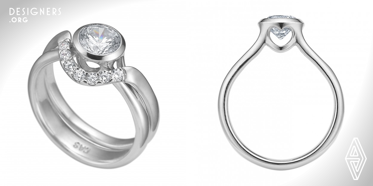 Two Forever is a Danish wedding set: Unlike most such sets, the two rings interlink like a hook and a loop, preventing them from moving autonomously. The engagement ring, called “Hiding Heart” has a classic look to it with a twist: Instead of the traditional prongs, the setting is closed, thereby protecting and visually enhancing the size of the gem. Light still flows through from the cut out hearts which hide on the sides of the setting. The wedding ring “Hooked on You” is studded with diamonds, describing a curve, which embraces the center diamond of the engagement ring when put together.