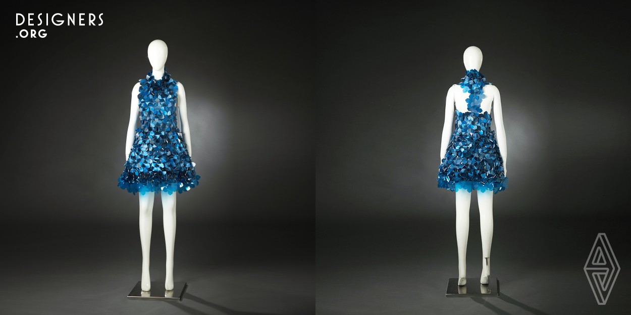 Digital technology today has created innumerable aesthetic and expressive changes in fashion design by introducing new media based on three-dimensional effects to it. This lenticular mini-dress shows a dynamic color change with a plankton-shaped module. Lenticular fabric sheets which present 3D displays create an illusion of depth from different angles, and module-based textile design highlights the iridescent color spreads from blue to black. Providing an oceanic feel, translucent PVC modules of two different graphic design are joined together with the lenticular modules without any sewing.
