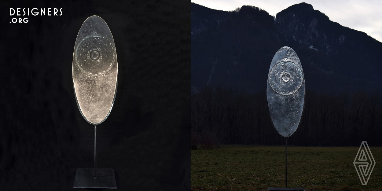 This object is both a lamp and a sculpture, depending on the intention and use of the viewer. An oval glass disc partly framed and mounted on a steel stand can be illuminated by LED. The glass was melted using a special technique with several layers at the GLASLICHTKLANG atelier in Urstall/Southern Bavaria. The object is suitable for indoor and outdoor use. 