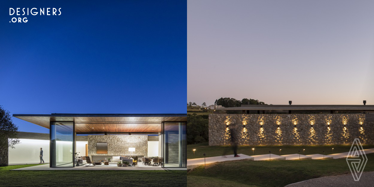 This house built to be a private getaway from the city has its main social areas surrounded by glass in a way that who is inside can fully contemplate the beautiful view of the woods. At the same time, the stone walls that embrace the rest of the residence guaranties the privacy of the intimate spaces. 
